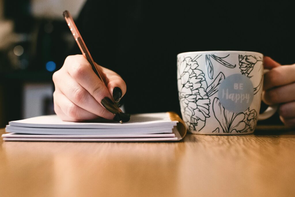 Femme qui écrit avec une tasse de café